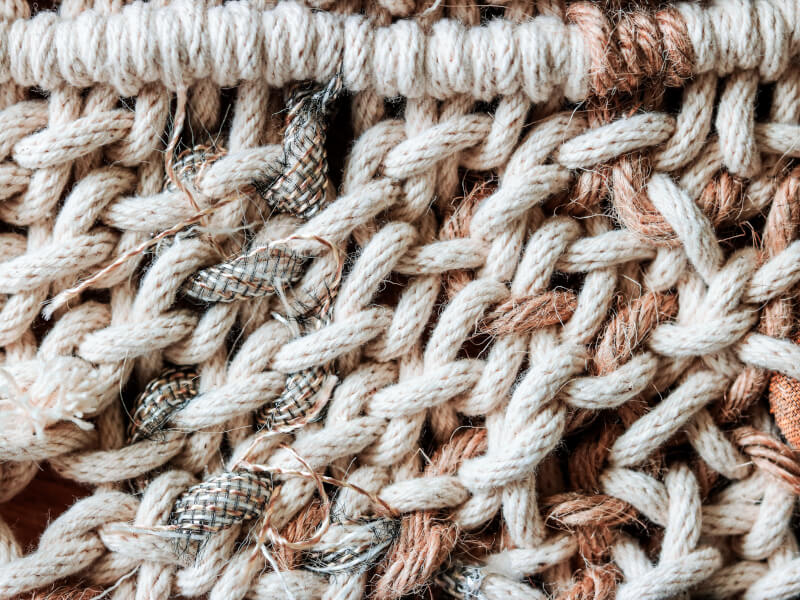A close up of a macrame piece in natural colours such as cream and brown